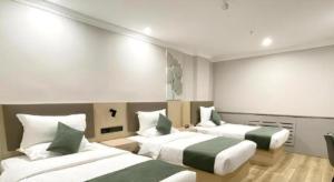 ein Hotelzimmer mit 2 Betten mit grüner und weißer Bettwäsche in der Unterkunft GreenTree Inn Xinjiang Uygur Autonomous Region Korla Bazhou Bus Terminal Beishan Road Express Hotel in Korla
