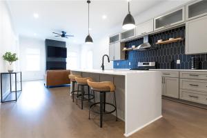 Una cocina con gabinetes blancos y taburetes de bar. en NEW Mercedes Benz Escape with Outdoor Theater & Bikes Minutes to Downtown & Top Attractions, en Atlanta