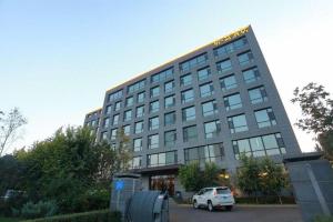ハルビン市にあるHarbin Ju Jian Hotelの建物の前に車が駐車されている