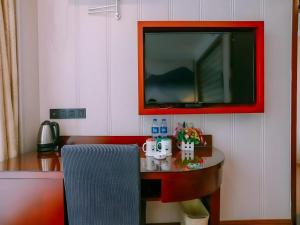 a room with a table with a tv on the wall at GreenTree Inn MaAnshan Economic Development District Hongqi South Road Express Hotel in Ma'anshan