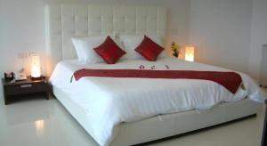 a bedroom with a large white bed with red pillows at Hua Hin Avenue Hotel in Hua Hin +125 photos