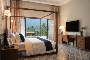 a hotel room with a bed and a desk and a television at The Ranch Kakkadampoyil - a VKation Experience in Kakkadampoyil