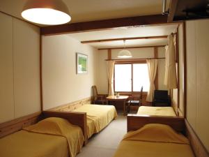 a room with two beds and a table and a window at ペンション木いちご PensionKiichigo in Zaō Onsen