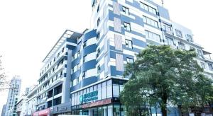 un edificio alto con un albero di fronte di City Comfort Inn Beihai RT-Mart High Speed Railway Station a Beihai