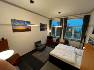 a bedroom with a bed and a chair and windows at Ecolodge Loft in Oesterdeichstrich