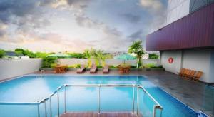 a large swimming pool with tables and chairs on a building at Ayola First Point Hotel Pekanbaru in Sultan Syarif Kasim II International Airport