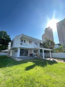 a white house with a green yard with two tall buildings at 5 beds 452sqm with Private garden Pet-friendly CCTV quiet and homey in Sathani Ban Hua Mak