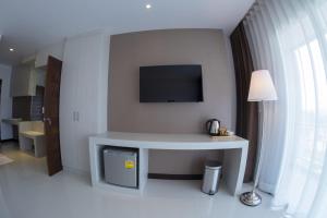 a living room with a table with a tv on the wall at Chaisaeng Villa in Sing Buri