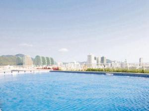 a large swimming pool with a city in the background at Poly Phoenix Hotel in Sanya
