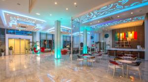 a lobby with tables and chairs in a building at Nicholas Color Hotel in Ayia Napa