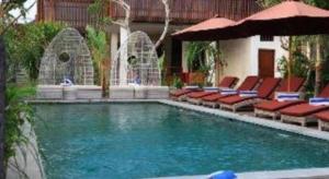 a swimming pool with chairs and an umbrella at Evita Villas in Ubud
