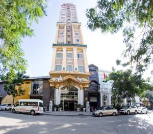 un grand bâtiment avec des voitures garées devant dans l'établissement Classic Hoang Long Hotel, à Hai Phong