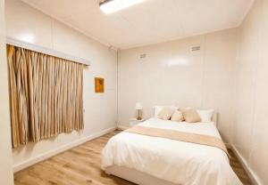 ein weißes Schlafzimmer mit einem großen Bett und einem Fenster in der Unterkunft Central Burwood Shared Stay in Sydney