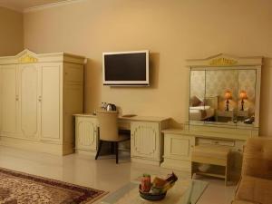 a living room with a desk and a tv on the wall at The Margangsa Hotel in Solo