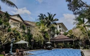 a swimming pool in front of a building with palm trees at The Oxalis Regency Hotel in Magelang