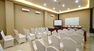 a conference room with white chairs and a screen at Hotel Betha Subang in Bandung