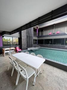 a pool with a table and chairs in front of a building at Nangfa Mini Hotel in Chiang Rai