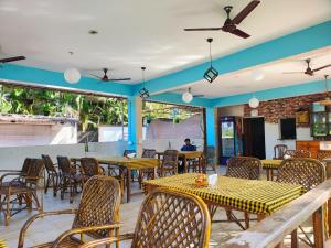 Un restaurante con mesas y sillas y un hombre al fondo. en Agonda Holiday Home, en Agonda