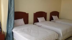 two beds in a room with white sheets at Serapis Hotel in Ḩilf
