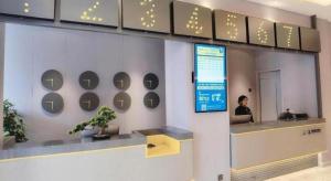a woman sitting at a counter in an office at 7 Days Inn Shanghai Yichuan Road in Shanghai