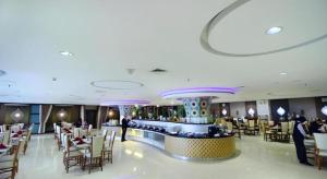 a restaurant with tables and chairs and a bar at Grand Qin Hotel Syariah in Banjarbaru