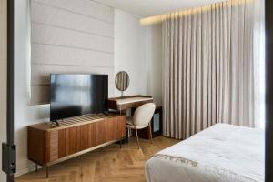 a bedroom with a bed and a desk and a television at Jewel TLV Hotel in Tel Aviv