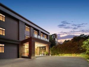 an exterior view of a building with a sunset at GreenTree Inn Fuyang Yijing International North Business in Fuyang