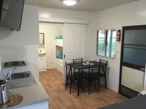 a kitchen with a table and chairs in a room at Colac Colac Caravan Park in Corryong