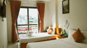 a hotel room with two beds and a balcony at LaCas Hotel Quy Nhon in Quy Nhon