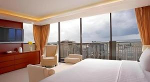 una camera da letto con un grande letto bianco e un balcone di Hotel Santika Makassar a Makassar Altre 130 foto