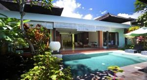 a villa with a swimming pool in front of a house at Tanjung Lesung Beach Hotel in Carita