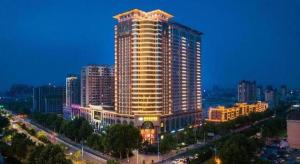 a large tall building in a city at night at Inzone Garlnd Hotel Zhangqiu in Jinan