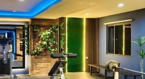a gym with a green accent wall with a bench at 89 Hotel Batam in Nagoya