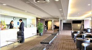丸亀市にあるHotel Anesis Seto-Ohashiのカウンターに2人が立っているロビー