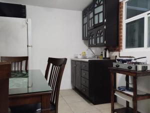 a kitchen with black cabinets and a table at Xaltepic tú casa in Amecameca de Juárez