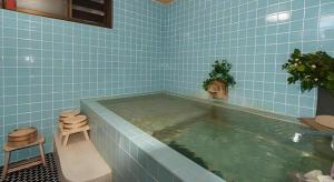 a blue tiled bathroom with a large pool of water at Country Inn Canadian House in Myoko