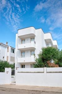 a white building with a white fence in front of it at Lavendel Apartments in Colonia Sant Jordi