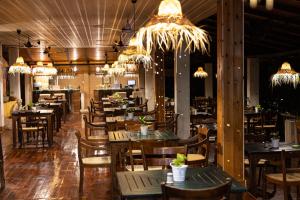 a restaurant with wooden tables and chairs and chandeliers at Jungle Village Unawatuna in Unawatuna