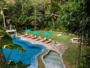 a swimming pool with lounge chairs and umbrellas at Jungle Village Unawatuna in Unawatuna