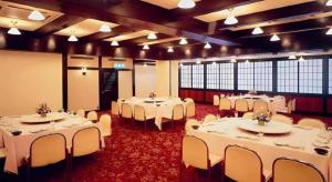 a banquet hall with white tables and white chairs at HotelNewYama in Nagano