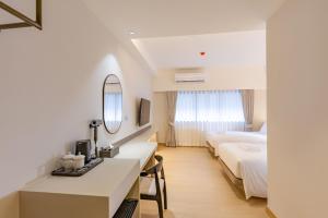 a hotel room with two beds and a desk with a mirror at The Bentley Hotel in Bangkok
