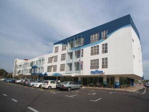 ein großes Gebäude mit auf einem Parkplatz geparkten Autos in der Unterkunft Hotel Zamburger Segamat (Previously Koptown Hotel Segamat) in Segamat