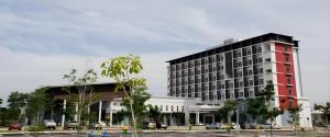 a large red and white building with cars in a parking lot at Hotel Scholar's Suites in Tanjung Malim