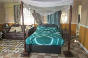 een slaapkamer met een hemelbed en een bank bij Nic's Inn in Freetown