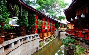 un edificio con sedie rosse e un fiume di fronte di James Joyce Coffetel·Lijiang Old Town Centeral a Lijiang