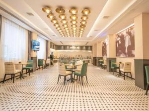 a dining room with tables and chairs and a chandelier at City Comfort Premier Hotel Xiaogan Anlu Railway Station Dongda Times Square in Xiaogan