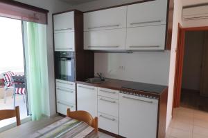 a white kitchen with white cabinets and a table at Apartment Omerovic in Novalja