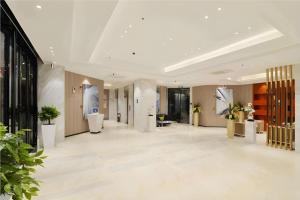 a lobby of a building with white floors and plants at City Comfort Inn Foshan Nanhai Avenue Guicheng Metro Station in Foshan