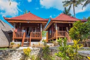 une maison sur la plage avec des palmiers dans l'établissement Secret Point Huts, à Nusa Lembongan