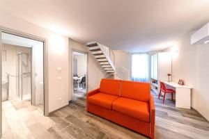 an orange couch in a living room with a staircase at Residenza Cavour - Appartamento D in Tirano